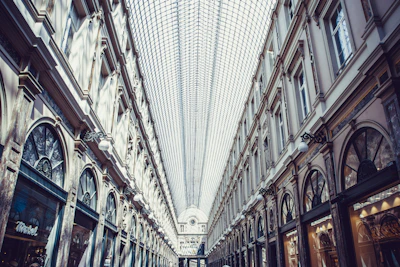 Modern shopping arcade interior with stylish storefronts and natural lighting.