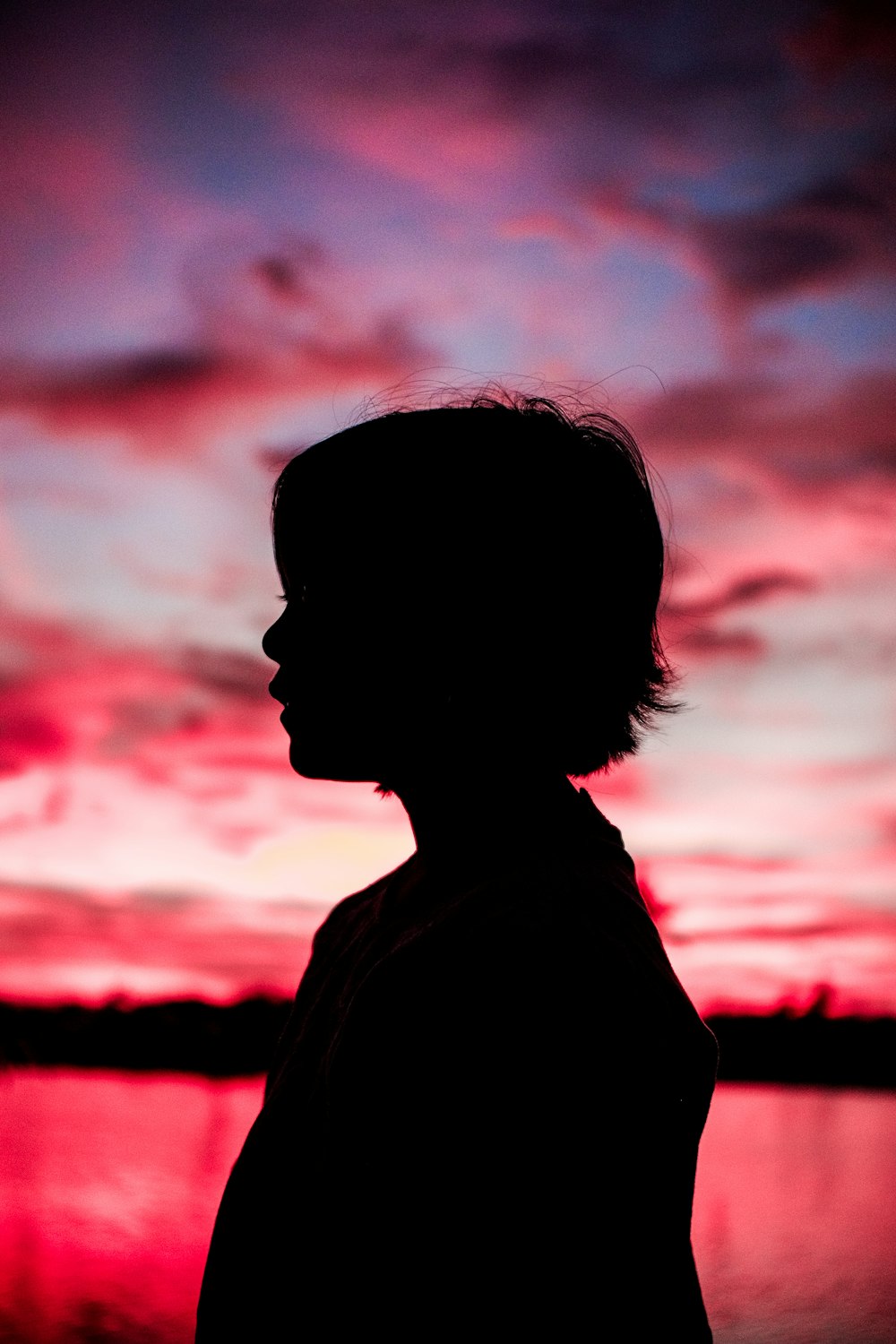 silhouette of child under pink sky at sunset