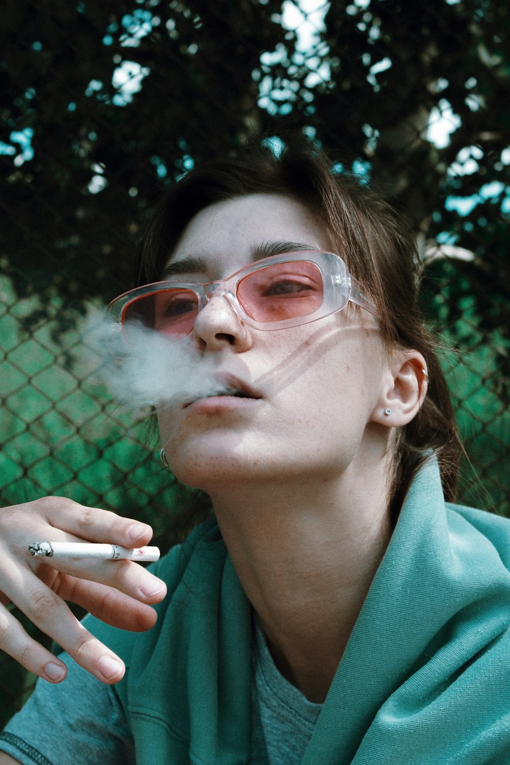 woman smoking behind chain fence