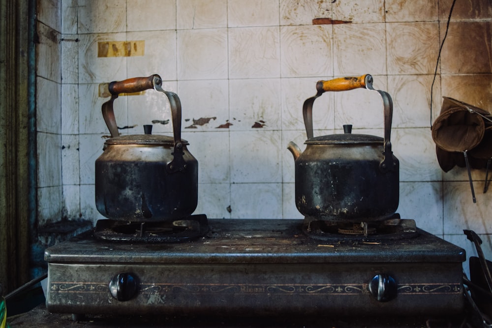 two gray teapots on gas stove