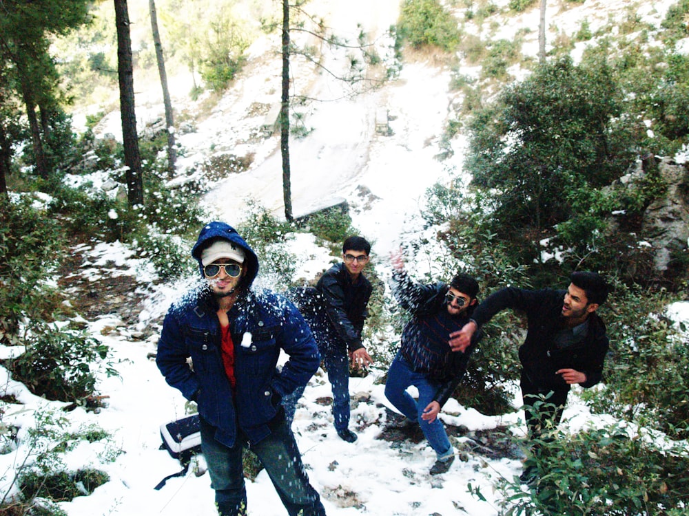 three men throwing snowballs on another man's back