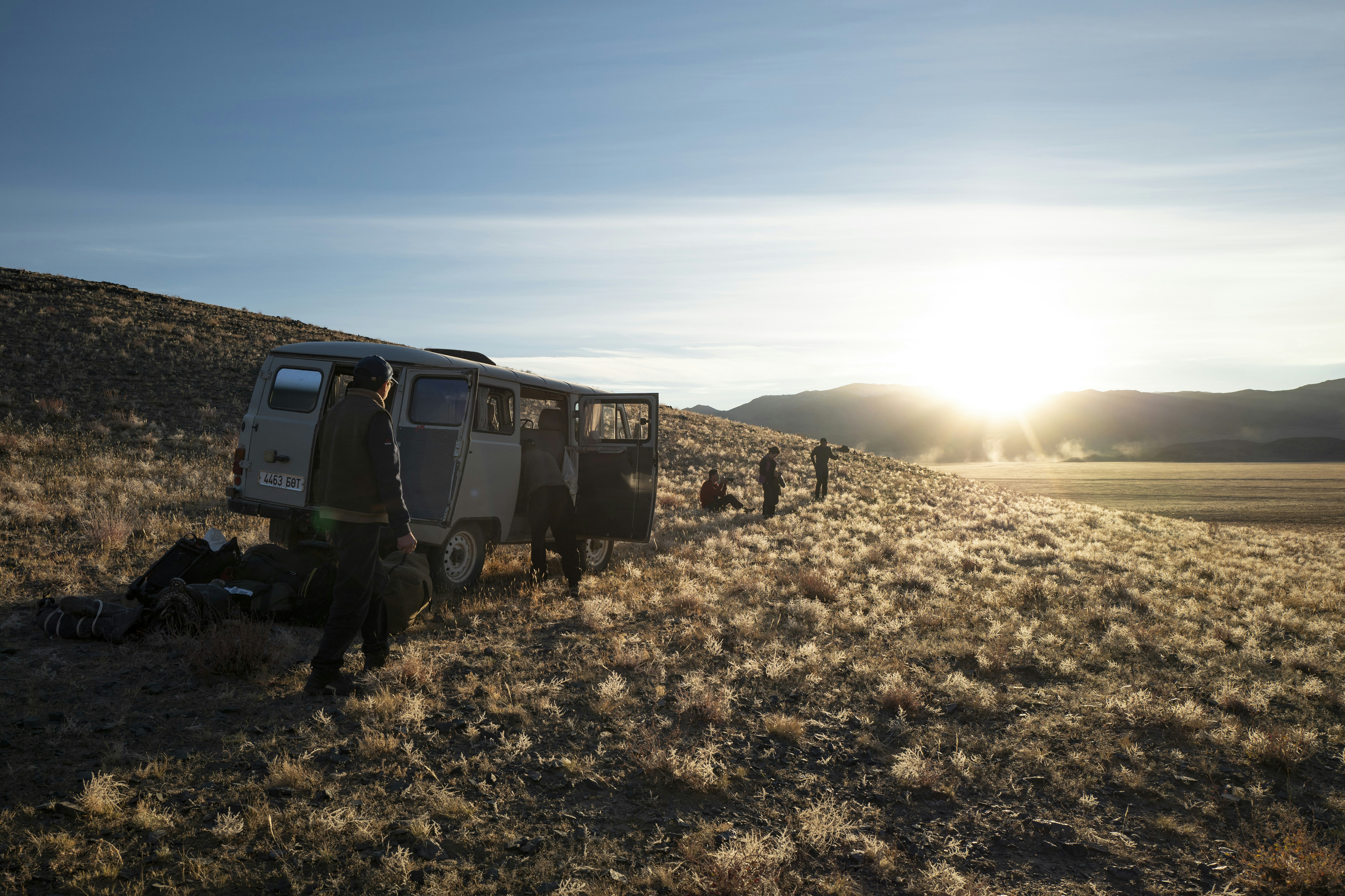 a group of people standing next to a van in a field, 