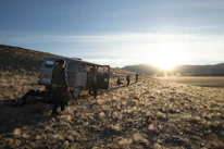 Friendly driver helping passengers board a comfortable tourist van at sunrise.