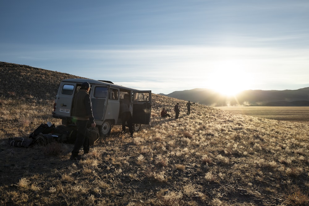 a group of people standing next to a van in a field