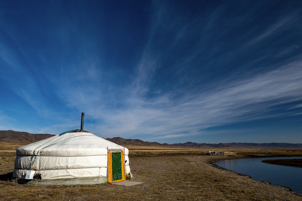 Una yurta seduta in un campo accanto a uno specchio d'acqua