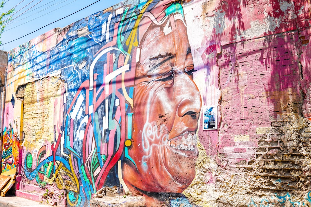une grande peinture murale du visage d’un homme sur un mur de briques
