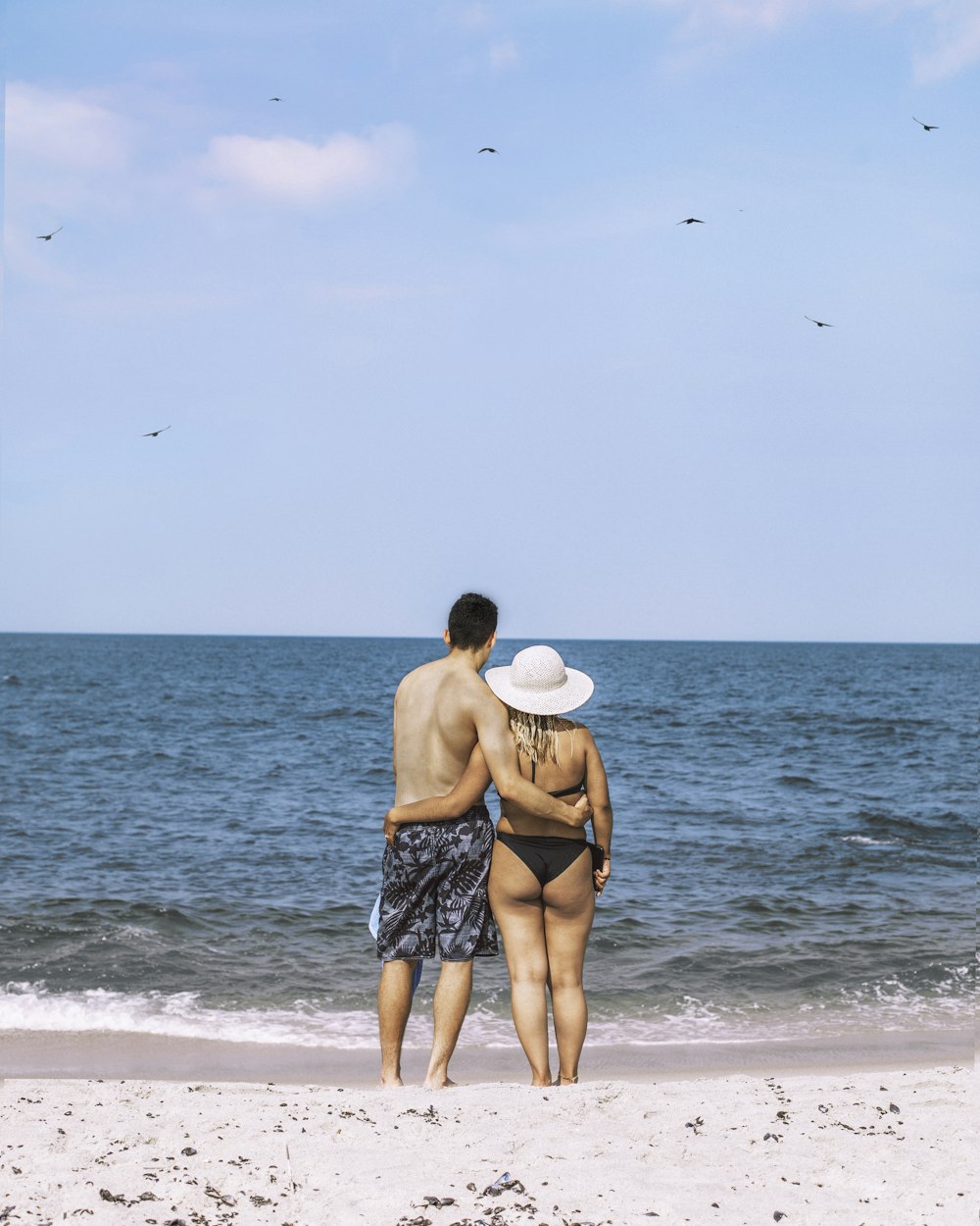 hombre y mujer abrazándose y de pie en la orilla del mar