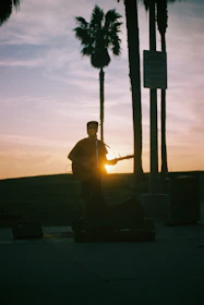 A musician playing a guitar next to a beautifully decorated floral arrangement at sunset.