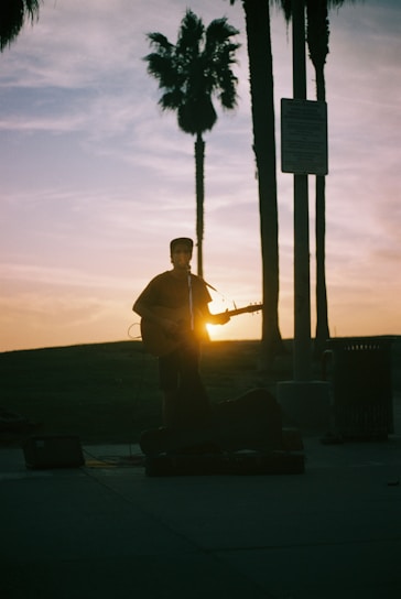 A vibrant photo capturing a candid moment of a street musician playing guitar at sunset.