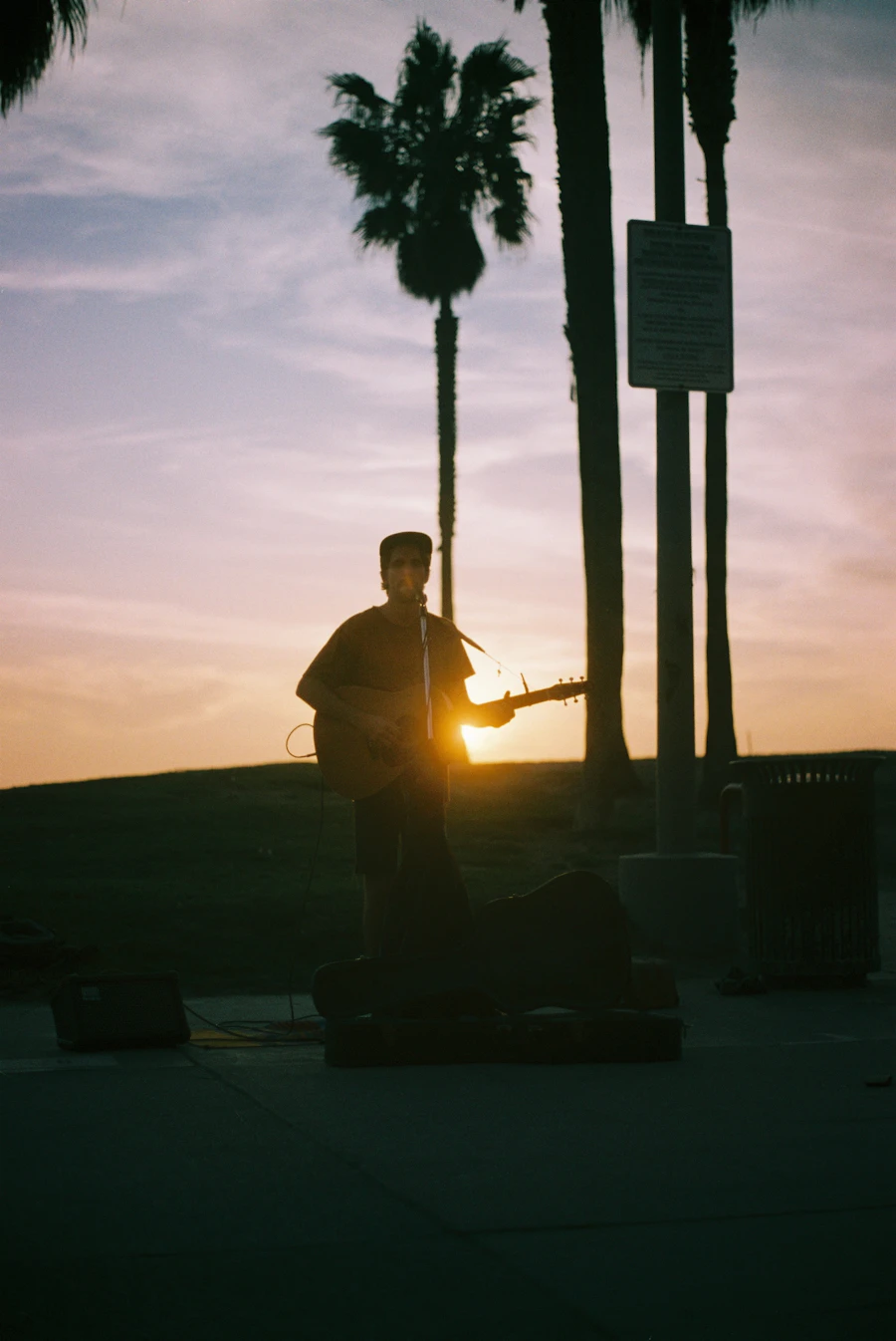 Street musician silhouetted against a golden sunset