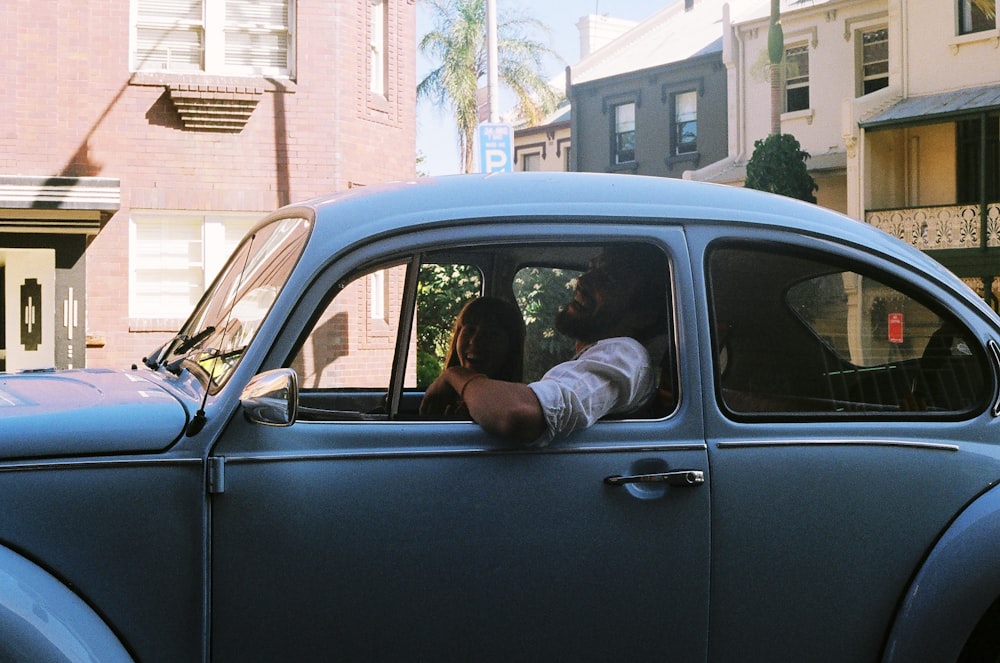 man and woman in blue classic Volkswagen Beetle