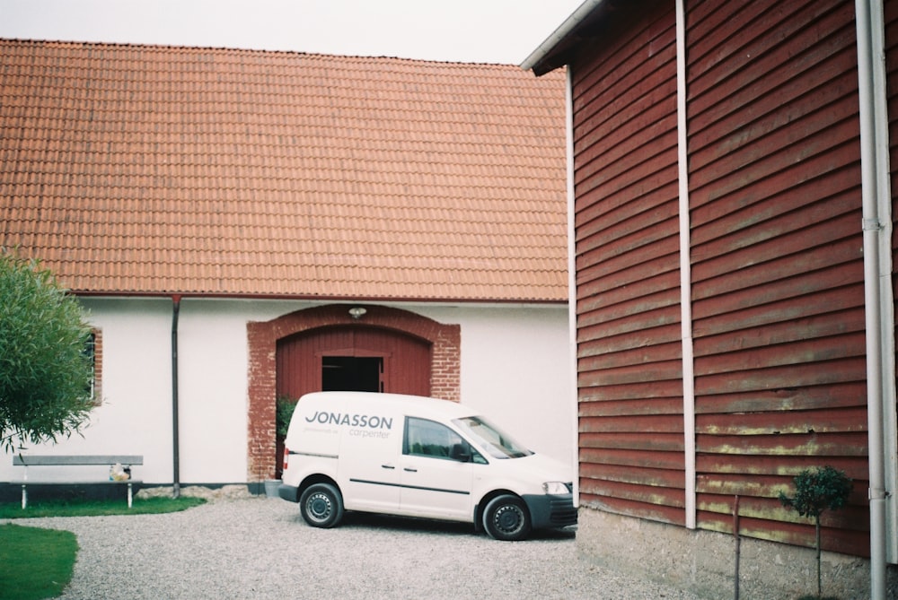 white car beside white and brown house