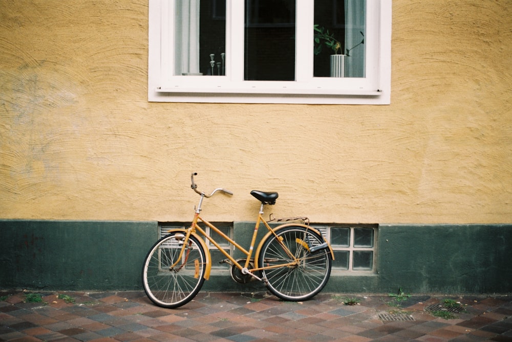 yellow city bike leaning on building wall during daytime