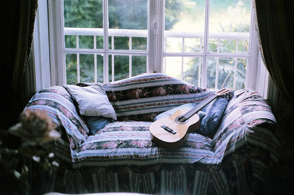 brown acoustic guitar on gray sofa