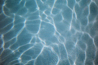 Sleek glass mosaic tiles shimmering under showroom lights in blue and green hues.