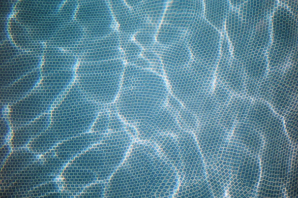 Sleek glass mosaic tiles shimmering under showroom lights in blue and green hues.