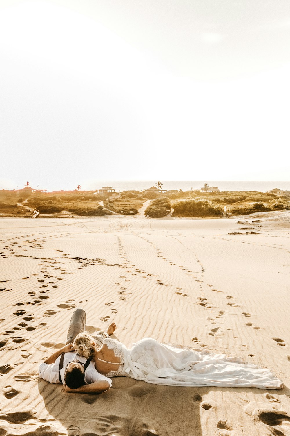 a woman laying on top of a sandy beach