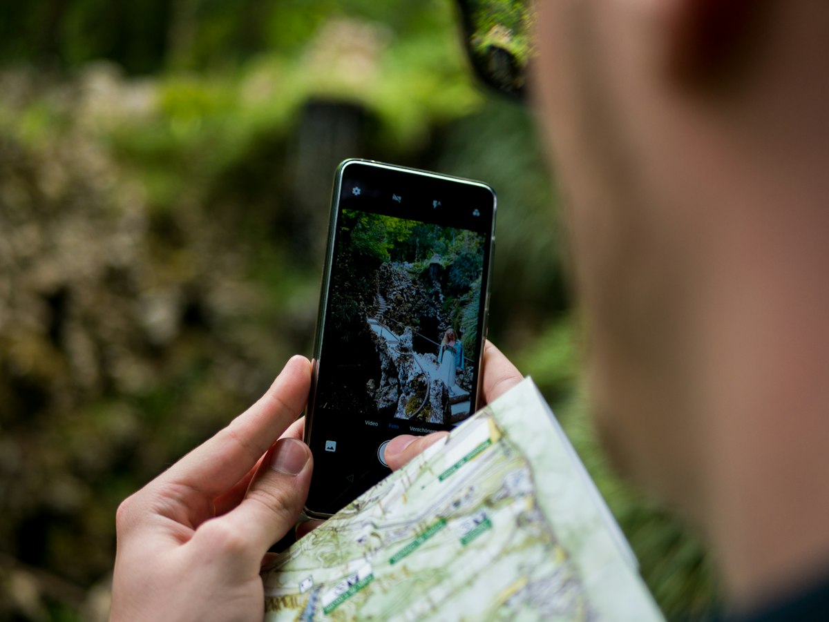 Persona sujetando un mapa de papel y un móvil