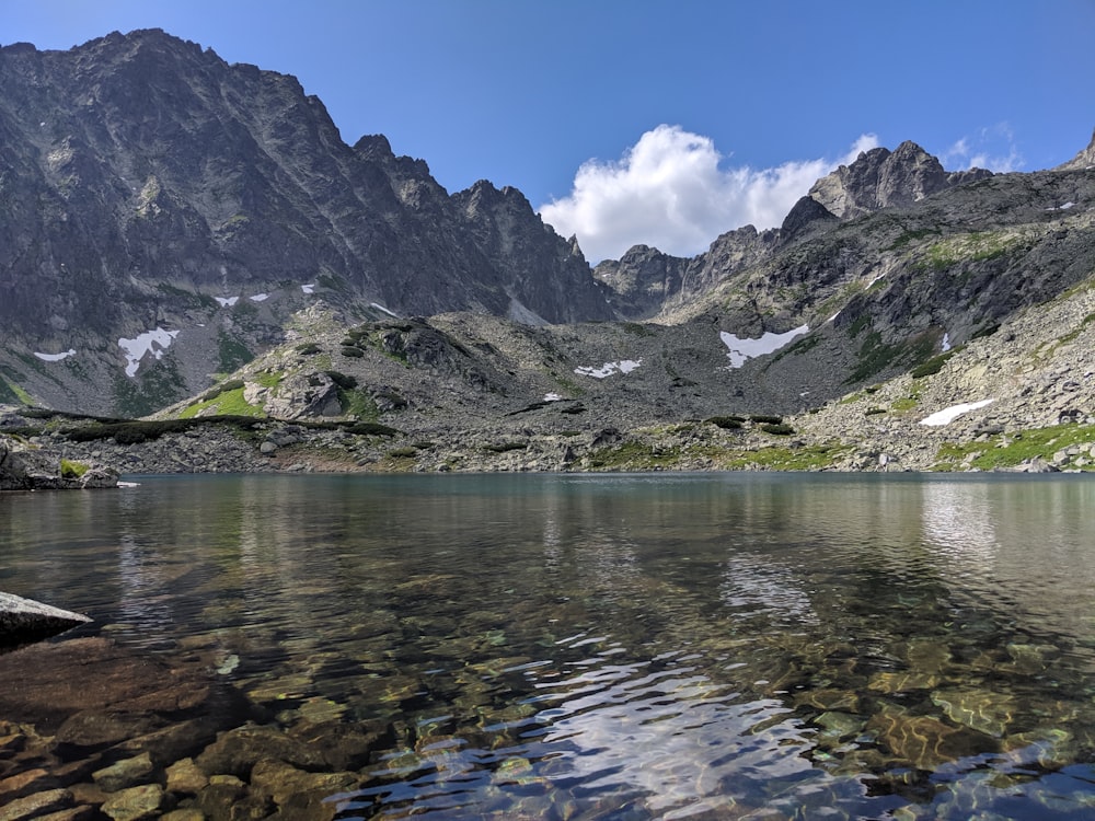 body of water surrounded with mountains at daytime