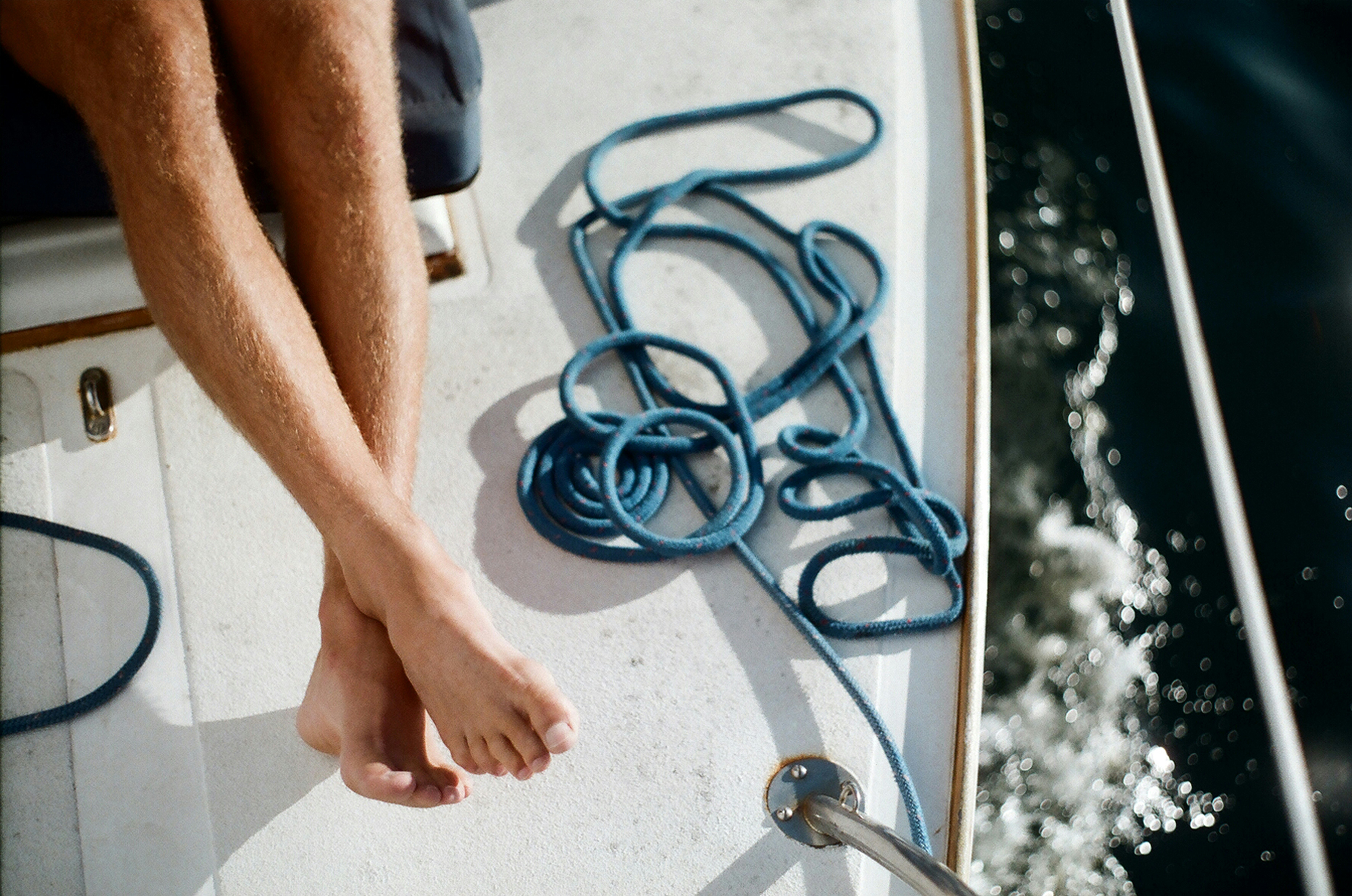 close-up photo of person sitting on boat beside blue hose