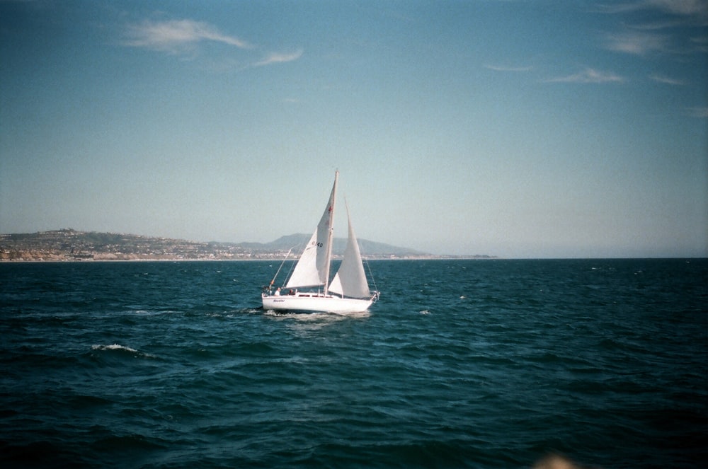 white sailboat on water under blue sky