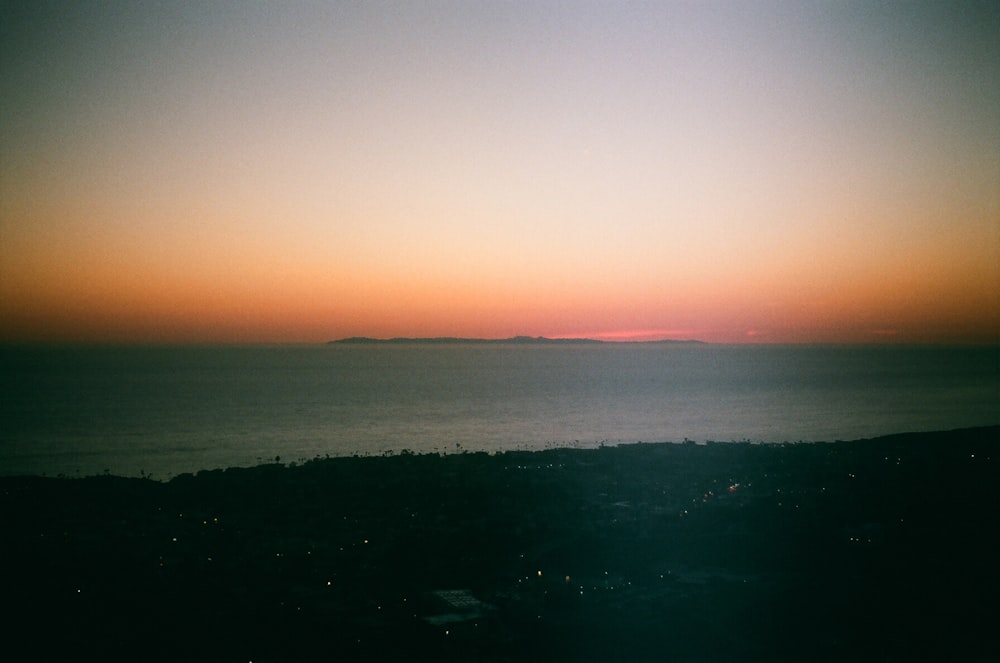 a view of the ocean at sunset from a hill