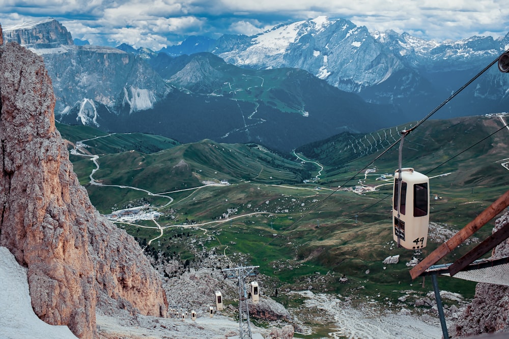 white and black cable cars near brown rock cliff