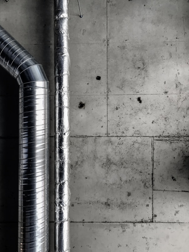 a black and white photo of pipes and a wall