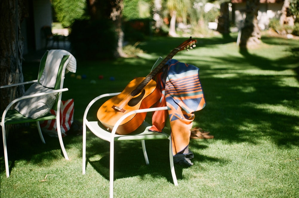 photo of brown and black dreadnought acoustic guitar on white armchair