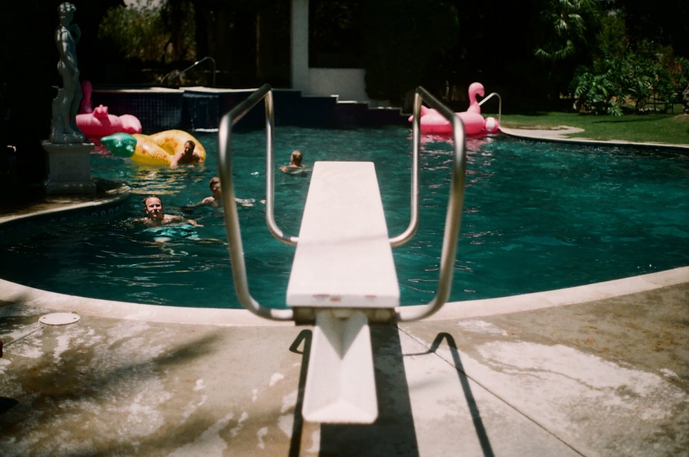 swimming pool diving board near people in pool