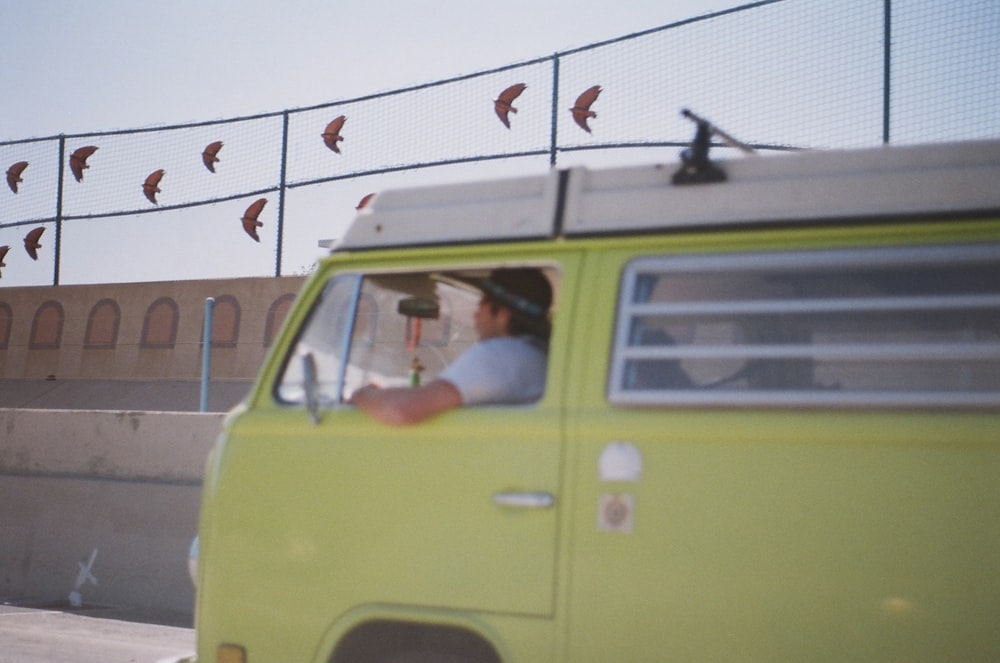 a man driving a green van down a street