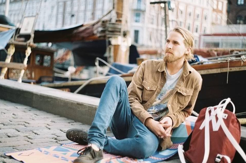 man in brown jacket leaning at the dock