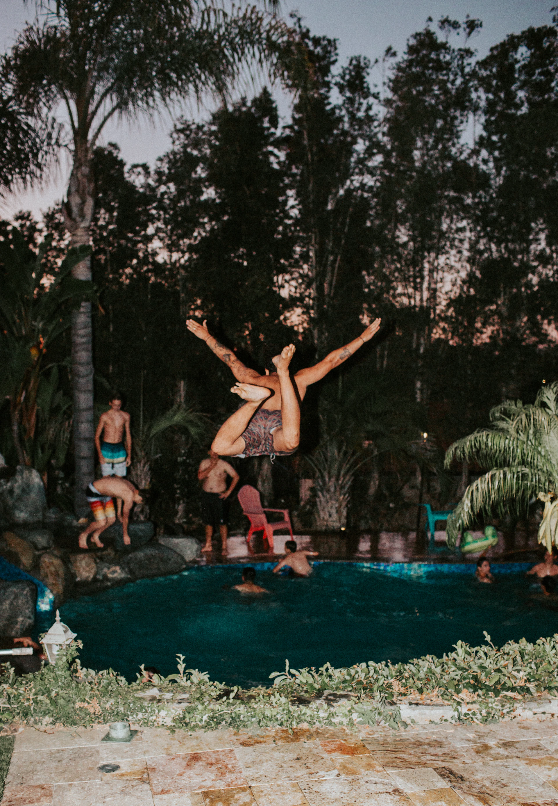 People leaping into a lit pool at night