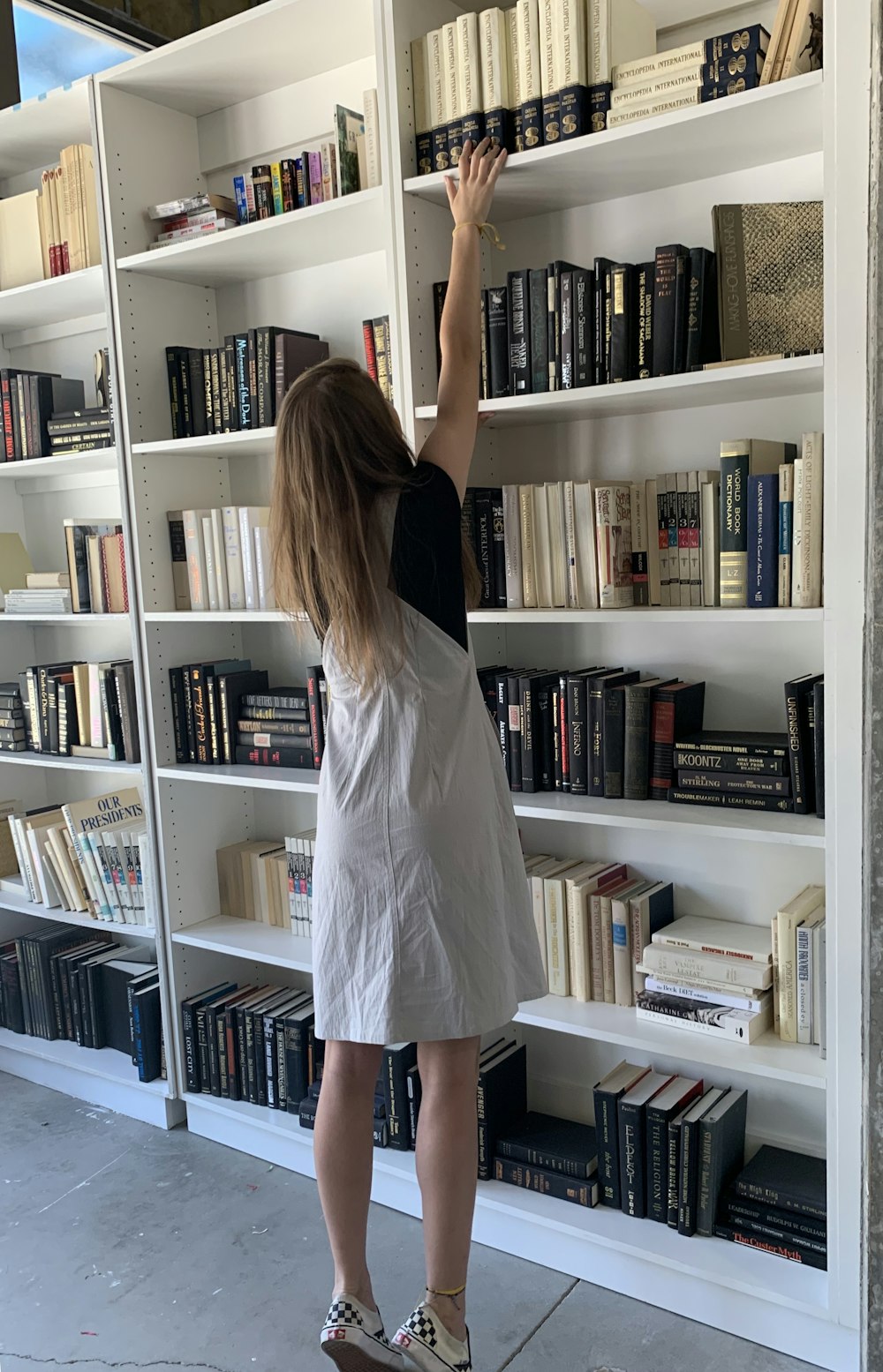 woman standing beside bookshelf
