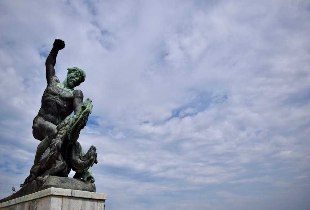 man fighting dragon statue under white skies