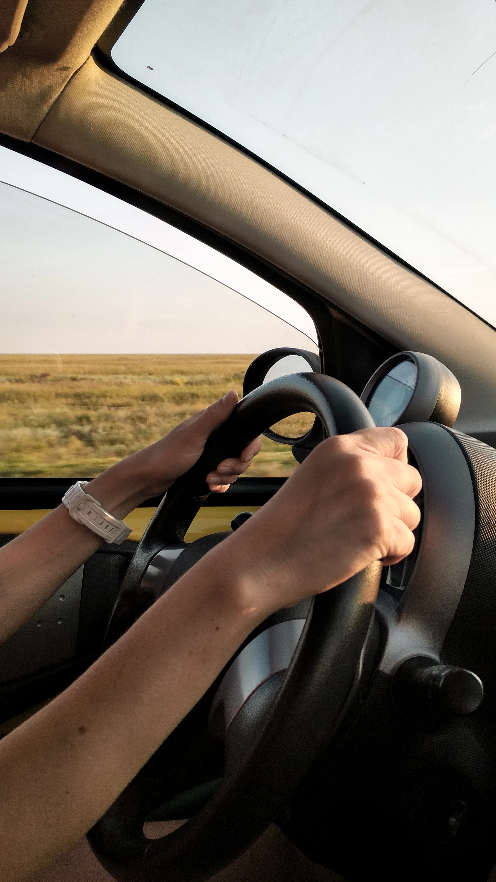 young driver's hands on a car steering wheel