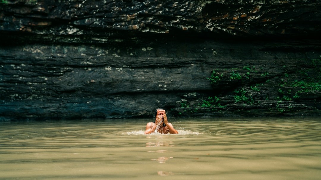 topless man swimming on body of water