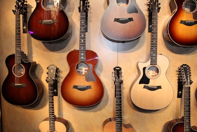 A vibrant display of various acoustic guitars hanging on a rustic wall, showcasing different wood finishes.