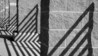 Artistic shot capturing the shadows cast by vertical metal bars on a beige wall, emphasizing texture and form.