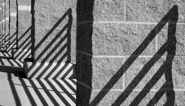 Artistic shot capturing the shadows cast by vertical metal bars on a beige wall, emphasizing texture and form.