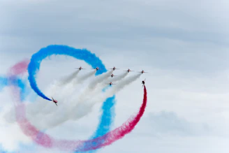 Dynamic airshow moment with planes performing synchronized maneuvers against a deep blue sky.