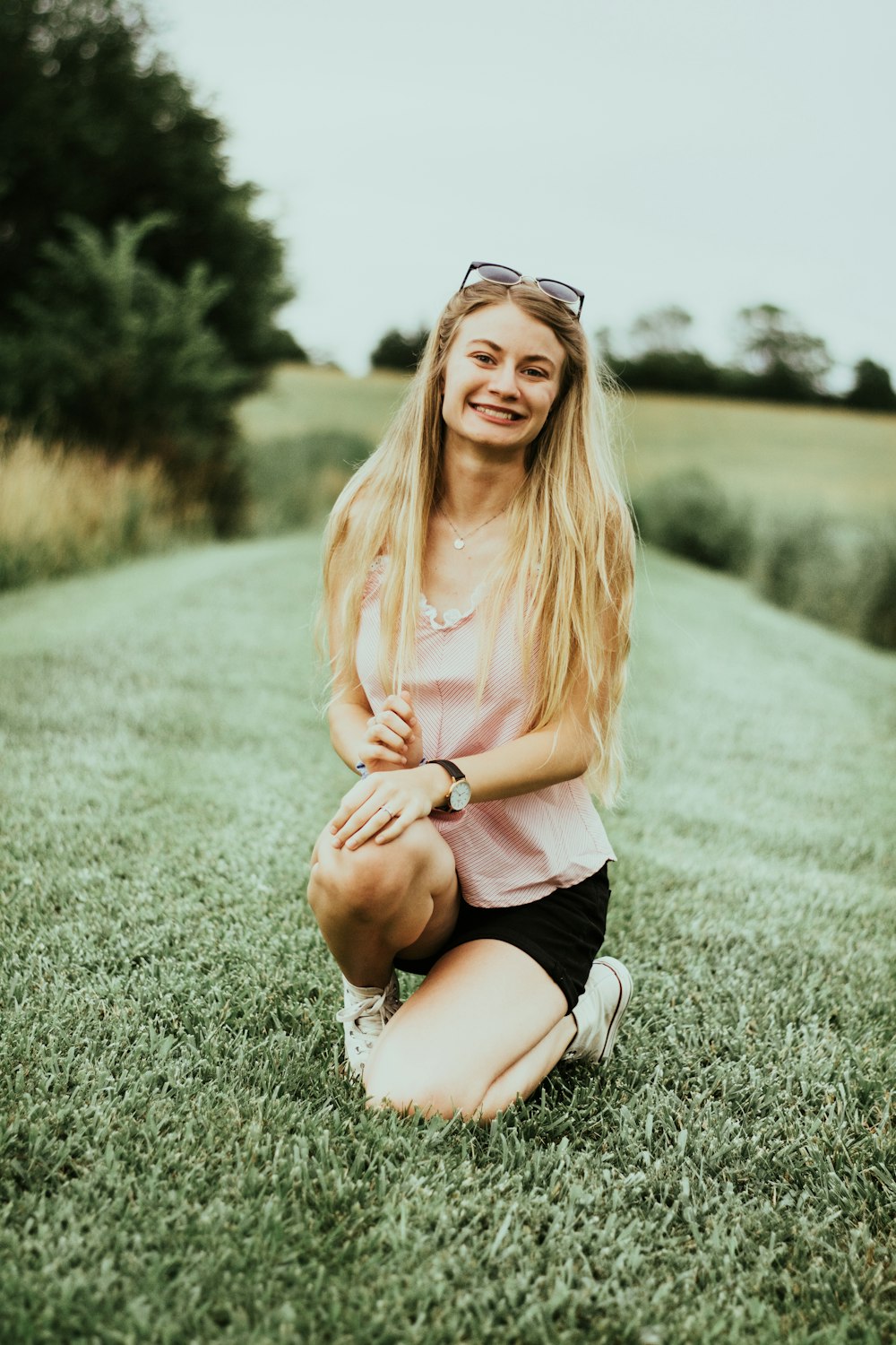 woman smiling and kneeling on green field