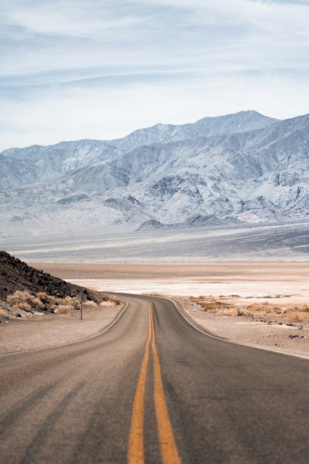 yellow lined road near snow covered mountain