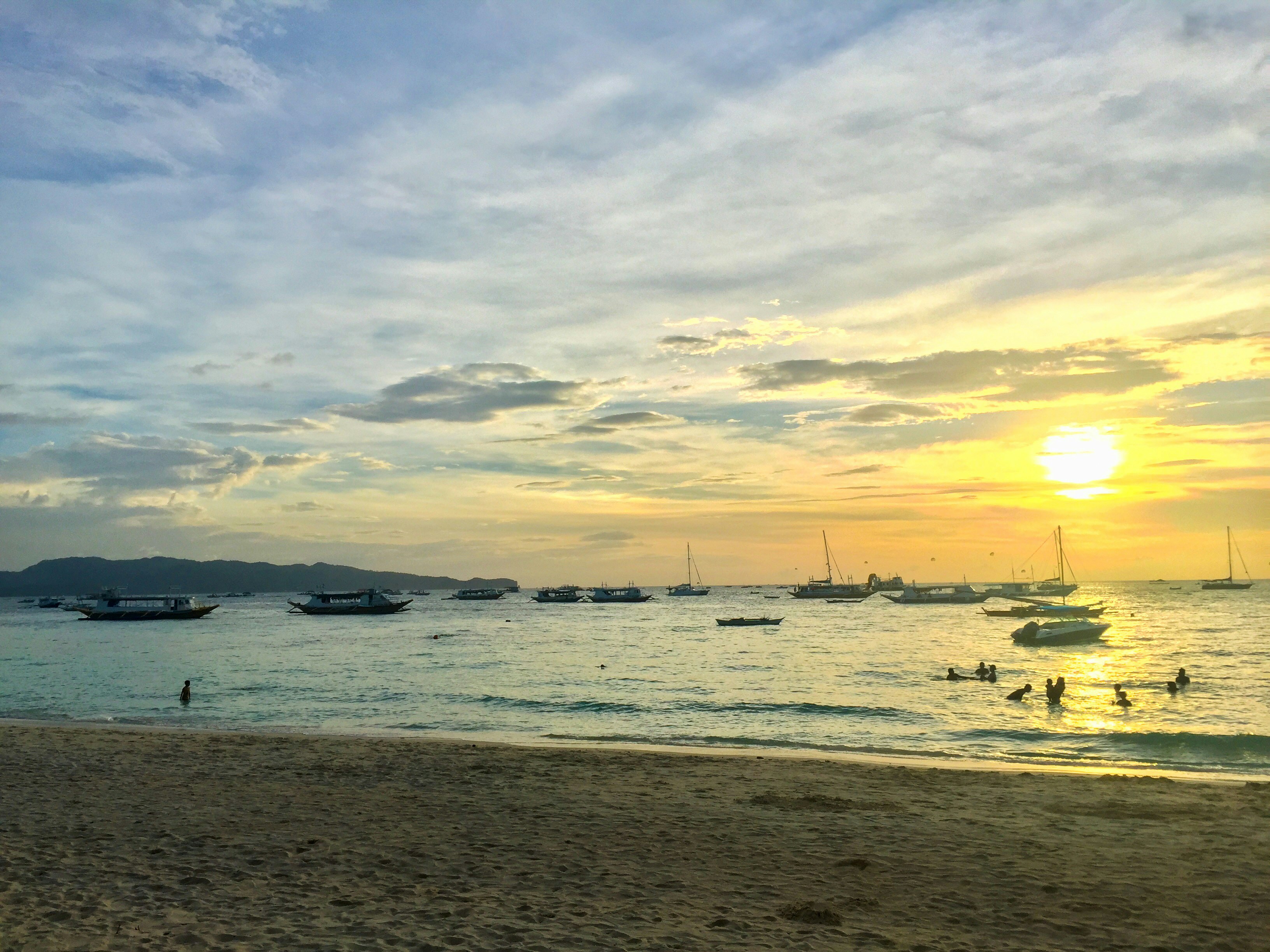 Beautiful golden sunset over Samal Island waters with silhouettes of boats and palm trees
