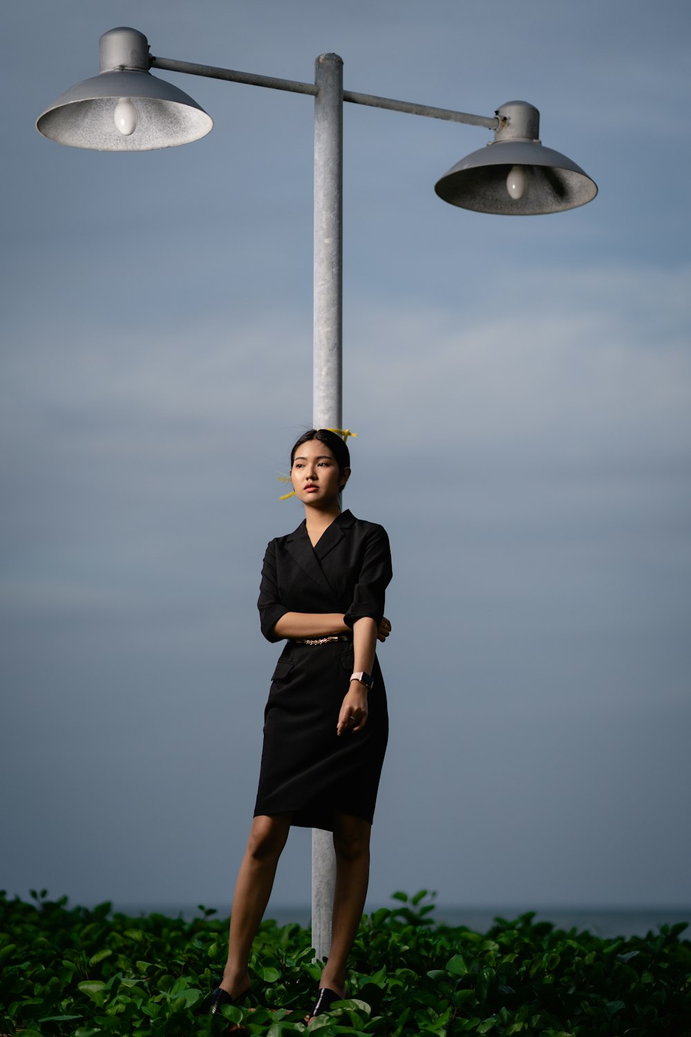 woman wearing black dress standing beside on gray electric post