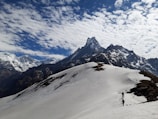 Snow-capped Himalayan peaks with trekkers making their way along a trail.