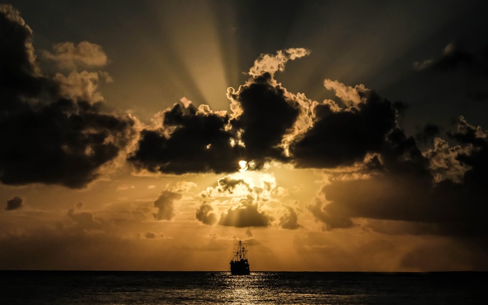silhouette of boat under clouds
