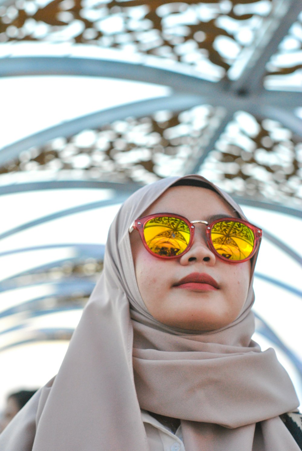 smiling woman wearing yellow lens sunglasses and brown scarf