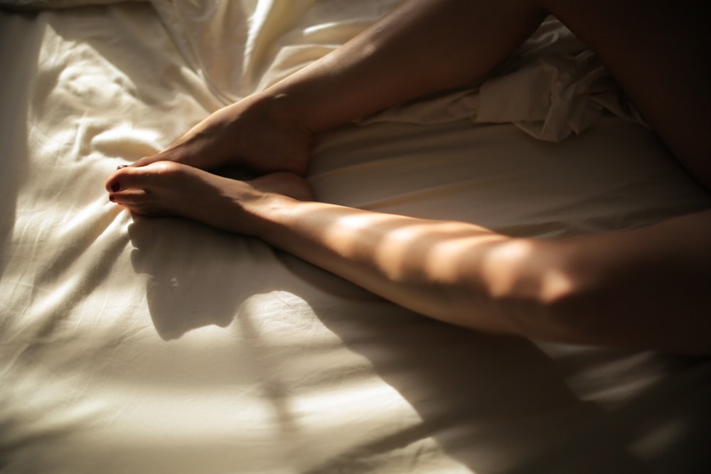 human feet on white bedspread close-up photography