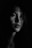 A person is captured in a moody, black and white portrait with dramatic lighting that highlights the face and expression.